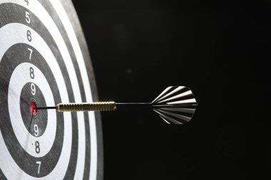 Hedef alınıyor. Karanlık arkaplanda ok olan dart tahtası, yakın plan