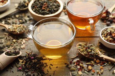 Tahta masada farklı bitki çayları ve kuru yapraklar, yakın plan.