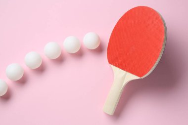 Masa tenisi raketi ve toplar pembe arka planda, düz yatıyordu.