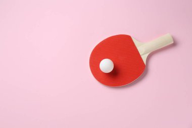 Pembe arka planda pinpon raketi ve top, üst manzara. Metin için boşluk