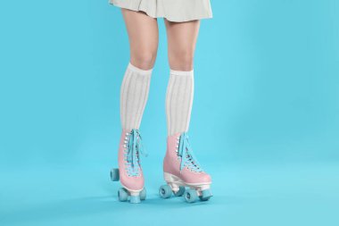 Açık mavi arka planda patenli kadın, yakın plan.