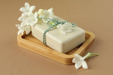 Açık kahverengi arka planda sabun ve yasemin çiçekleri, yakın plan.