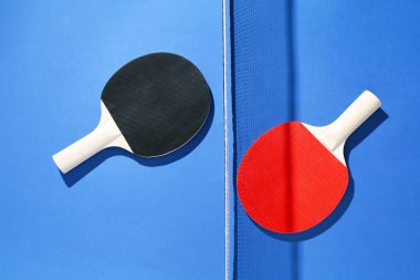 Masa tenisi raketleri ve mavi arka planda net, düz yatıyordu.