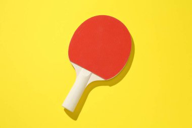 Sarı arka planda bir ping pong raketi, üst manzara.