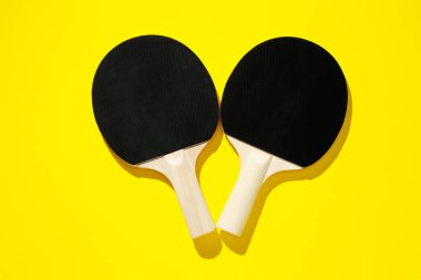 Sarı zemin üzerinde pinpon raketleri, üst görünüm