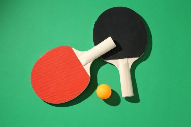 Yeşil zemin üzerinde pinpon raketleri ve top düz yatıyordu.