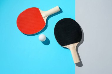 Renkli arka planda pinpon raketleri ve top, üst görünüm