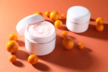 Kavanozlar dolusu nemlendirici vücut kremi ve turuncu arka planda toplar, yakın plan.