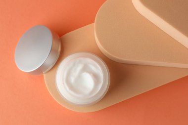 Turuncu arka planda kavanozda nemlendirici vücut kremi sunumu.