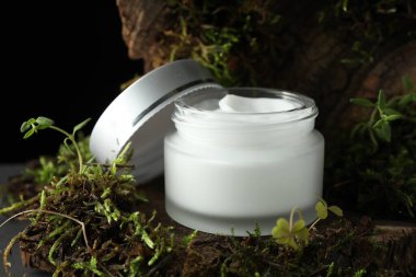 Ağaç kabuğunda bitkilerle birlikte nemlendirici vücut kremi, yakın plan.