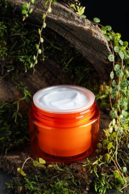 Ağaç kabuğunda bitkilerle birlikte nemlendirici vücut kremi, yakın plan.