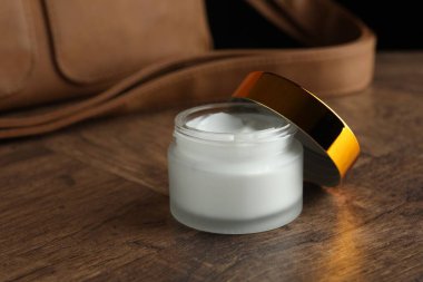 Bir kavanoz nemlendirici vücut kremi ve deri çanta ahşap masada, yakın plan.
