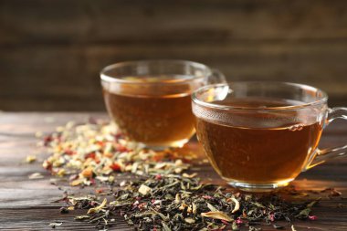 Bitki çayı ve kuru yaprakları ahşap masaya serpmek, yakın plan.