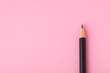 Açık pembe arka planda keskin grafit kalem, üst manzara. Metin için boşluk