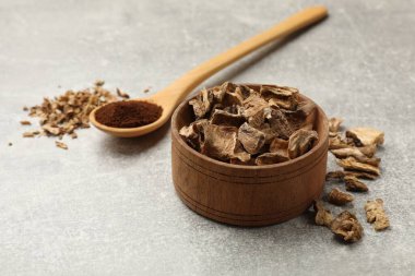 Kuru hindiba kökleri kasede ve kaşıkta toz ve gri desenli masa.