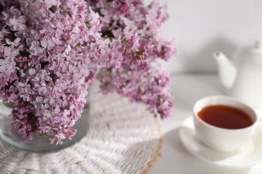 Cam vazoda güzel leylak çiçekleri ve masada çay, yakın plan.