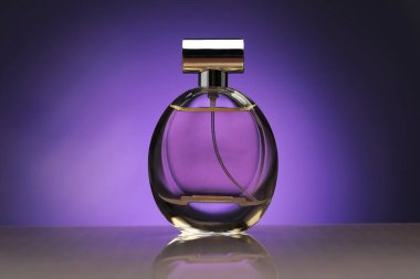 Ayna yüzeyinde mor renge karşı bir şişe parfüm.