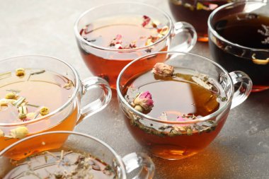 Gri masadaki cam fincanlarda Aromatik bitki çayı, yakın plan.