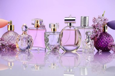 Ayna yüzeyinde mor arka planda parfüm şişeleri ve leylak çiçekleri