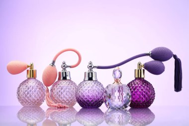 Ayna yüzeyinde soluk menekşe eğimli arka planda parfüm şişeleri