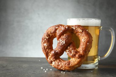 Lezzetli kraker ve koyu dokulu masada bir bardak bira. Gri arka planda, yakın plan. Metin için boşluk