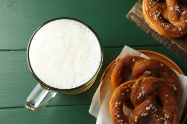 Lezzetli krakerler ve yeşil ahşap masada bir bardak bira.