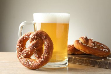 Lezzetli krakerler ve bir bardak bira ahşap masada, gri arka planda, yakın planda.