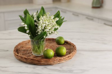 Bir buket güzel vadi zambağı ve beyaz mermer masa üzerinde limonlar.