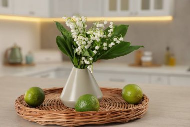 Vazodaki güzel zambak buketi ve mutfaktaki ahşap masa üzerindeki limonlar.