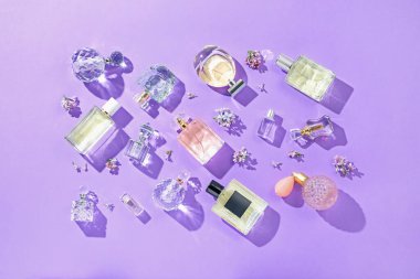 Düz kompozisyon, parfüm şişeleri ve mor arka planda leylak çiçekleri vardı.