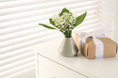 Vadi çiçeklerinin güzel zambakları ve kapalı alanda beyaz masa üzerinde hediye. Metin için boşluk