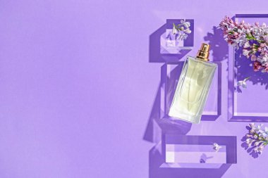 Düz kompozisyon, mor arka planda parfüm şişesi ve leylak çiçekleri vardı. Metin için boşluk