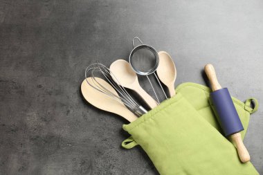 Mutfak aletleri farklı, fırın eldivenleri gri masada, düz yerde. Metin için boşluk