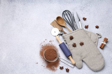 Farklı mutfak aletleri fırın eldivenlerinde, kakao tozu, tarçın ve anason yıldızları ışık masasında, düz yerde. Metin için boşluk