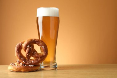 Lezzetli krakerler ve ahşap masada bir bardak bira bej renkli arka planda, yakın plan. Metin için boşluk