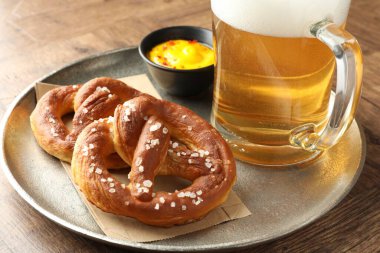 Lezzetli krakerler, sos ve cam bardak biralar ahşap masada, yakın plan.