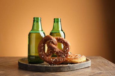 Lezzetli krakerler ve bira şişeleri ahşap masa üzerinde bej renkli gradyan arka plan, yakın çekim