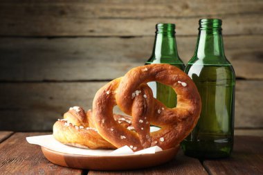 Lezzetli krakerler ve bira şişeleri ahşap masada, yakın plan.