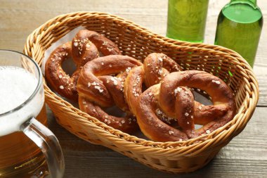 Sepette lezzetli krakerler ve ahşap masada bira, yakın plan.