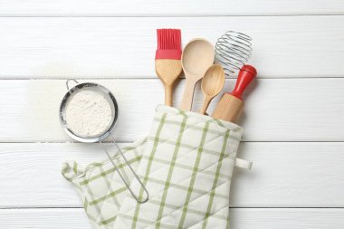 Farklı mutfak aletleri fırın eldiveni ve un beyaz ahşap masa, düz yatıyordu.