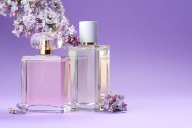 Parfümlü şişeler ve mor arkaplanda leylak çiçekleri, yakın plan. Metin için boşluk