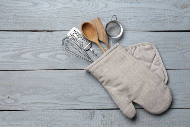 Fırın eldivenindeki farklı mutfak aletleri açık gri ahşap masa, üst manzara. Metin için boşluk