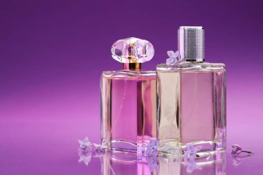 Parfümlü şişeler ve ayna yüzeyindeki leylak çiçekleri renk değişimine karşı, yakın plan. Metin için boşluk