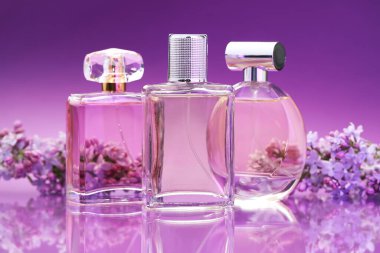 Parfümlü şişeler ve ayna yüzeyinde leylak çiçekleri renk değişimine karşı, yakın plan