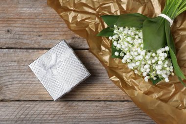 Bir buket güzel vadi zambağı ve ahşap arka planda bir hediye.