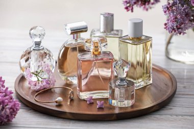 Beyaz ahşap masada, parfüm şişeleri ve leylak çiçekleri, yakın plan.