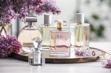 Beyaz ahşap masada, parfüm şişeleri ve leylak çiçekleri, yakın plan.