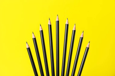 Sarı arkaplanda bir sürü keskin grafit kalem var.