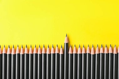 Sarı arka planda bir sürü keskin grafit kalem, düz bir zemin. Metin için boşluk