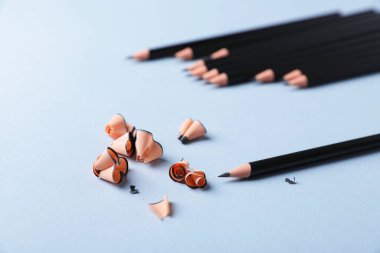 Açık gri arkaplanda keskin grafit kalem ve talaş, yakın plan.